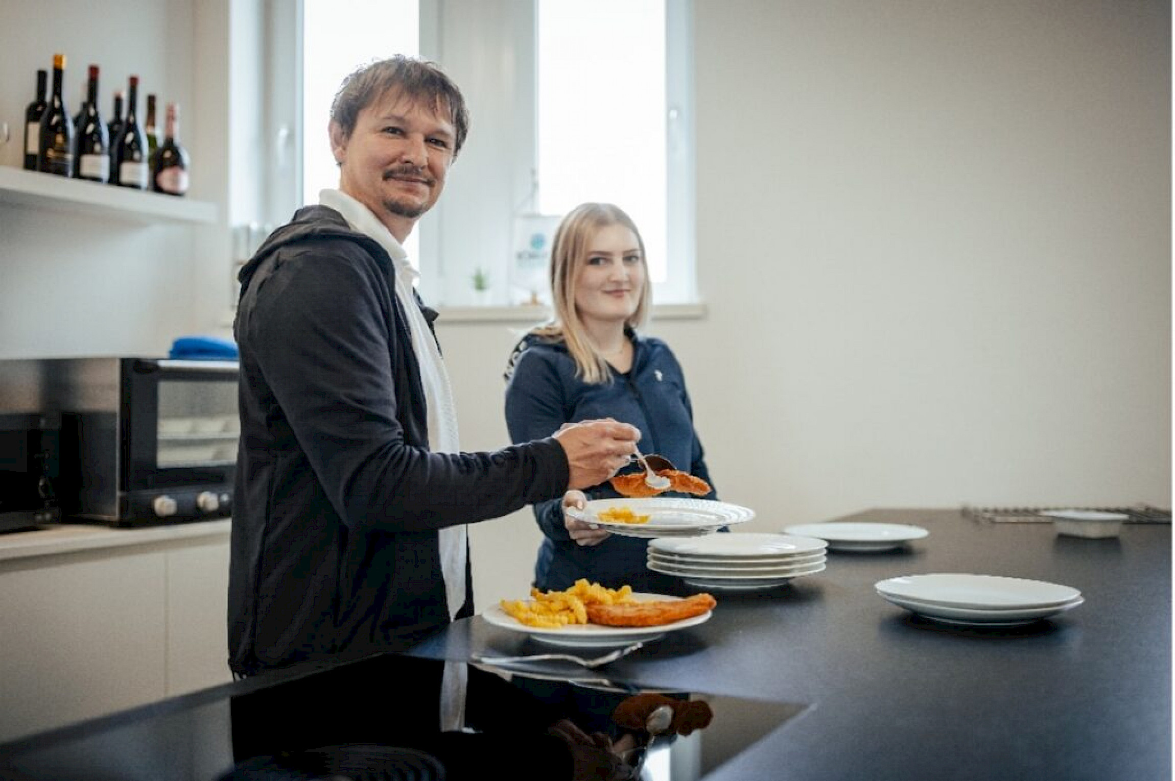 Oliver Bauer (Bereichsleiter Qualitätsmanagement) und Lehrling Elena Walser bei der Zubereitung des Mittagessens in der offenen Küche.